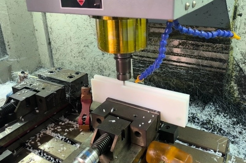 CNC machine machining UHMWPE block with visible shavings and surface finish